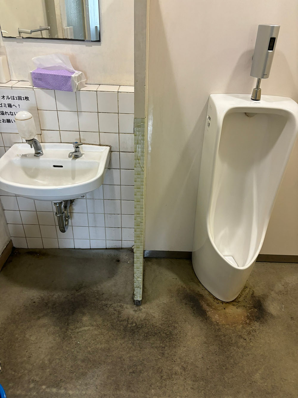 汚れたトイレの床と小便器